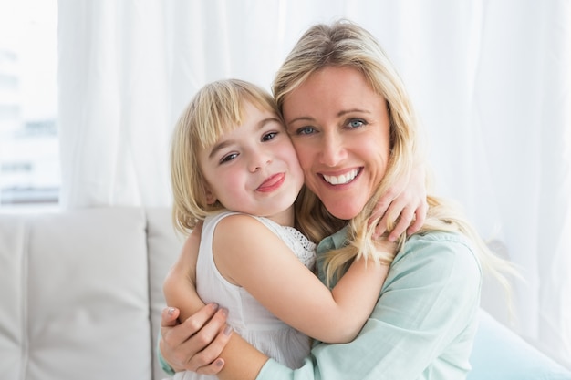 Happy mother and daughter hugging on the couch at home in the living room