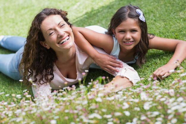 Happy mother and daughter lying on the grass