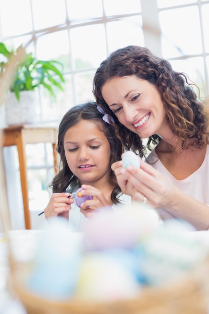 Happy mother and daughter painting easter eggs 