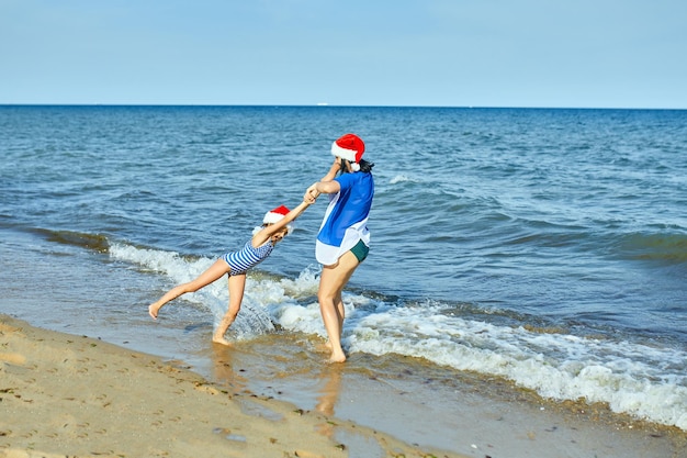 Happy mother and daughter in Santa christmas hats having fun