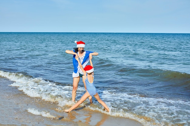 Happy mother and daughter in Santa christmas hats having fun