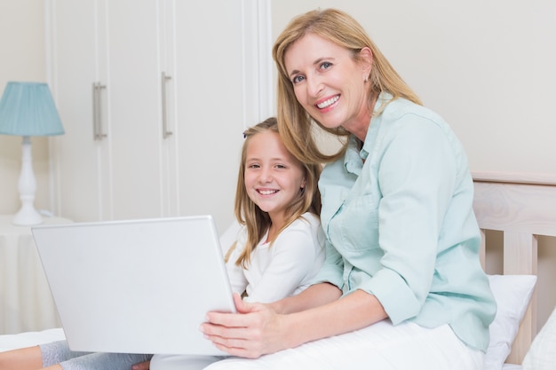 Happy mother and daughter using laptop