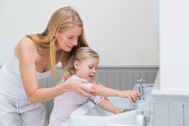 Happy mother and daughter washing hands