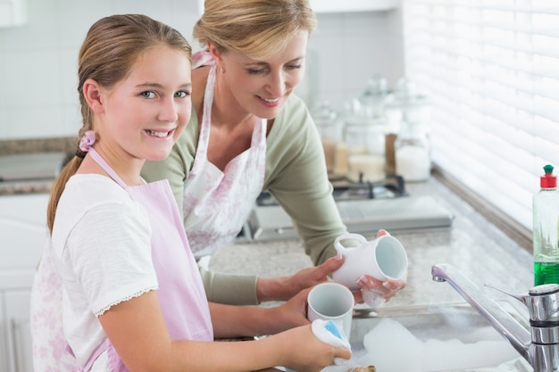 Happy mother and daughter washing up together 