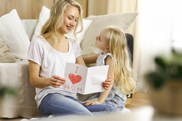 Happy mother day Child daughter congratulates mom and gives her postcard with heart drawing Family and childhood concepts