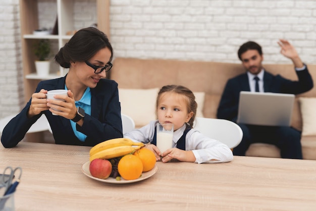 Happy mother drinks tea and offended child drinks milk