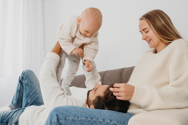 Happy mother and father spending time with their baby on the sofa