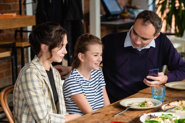 happy mother, father and their girl having dinner and talking at a restaurant or cafe