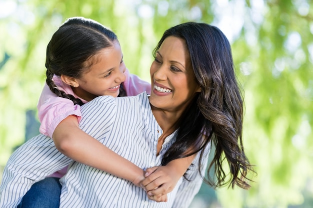 Happy mother giving piggyback ride to her daughter