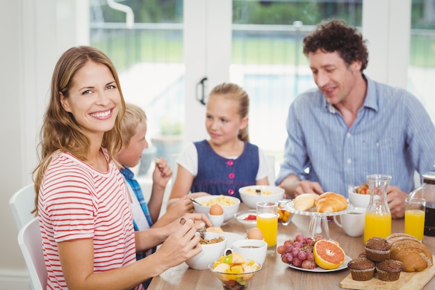 Happy mother having breakfast with family at table