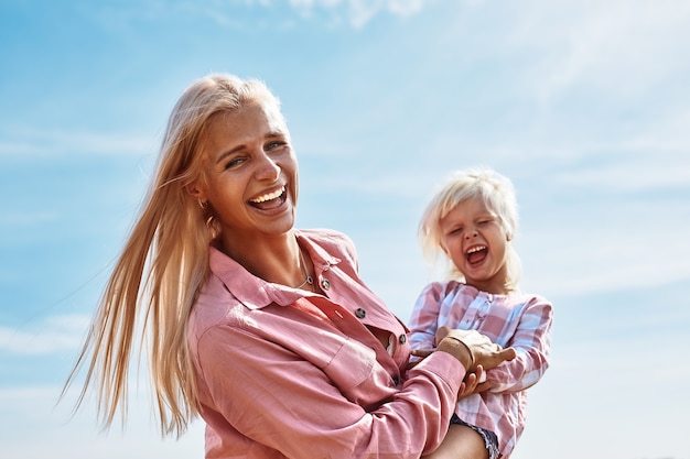 Happy mother holding baby smiling on a wheat field in sunlight