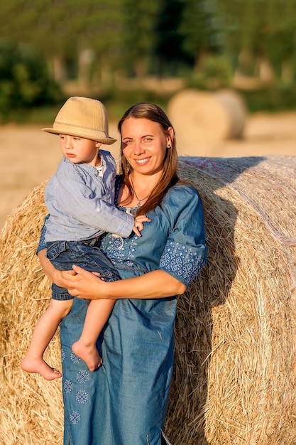 Happy mother holding her little son in her arms in a grain field Lovely mother and her son having fun Happy family