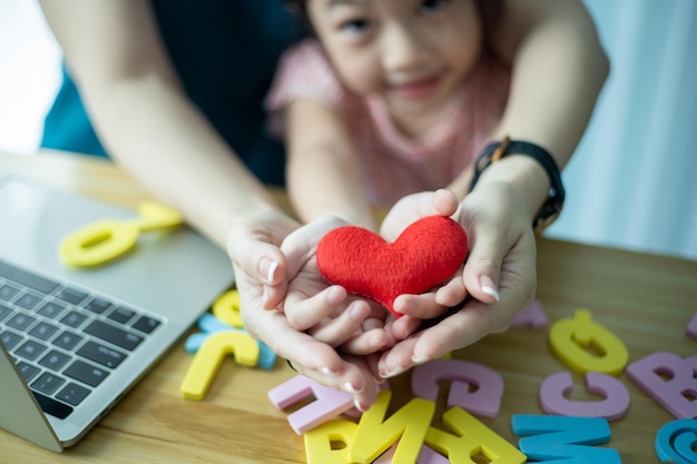 Happy mother and preschool daughter playing with set of colors letters