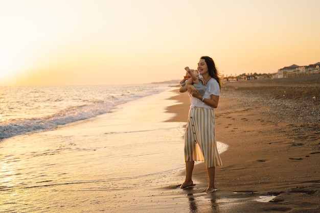 Happy mother's day Beautiful mother and baby play on the beach Mum and her Child together enjoying sunset Loving single mother hugs cute little son