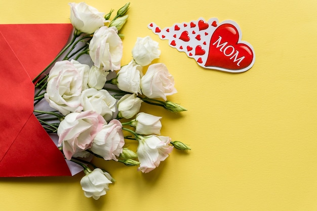 Happy Mother's Day.Bouquet of white eustoma flowers with red heart on bright background.Spring flowers for Mother's Day.