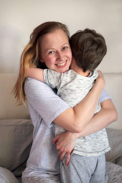 Happy mother's day. Child boy congratulates mom and gives her flowers tulips and postcard. Mum and son smiling and hugging. Family holiday and togetherness. Mother's day greeting concept.