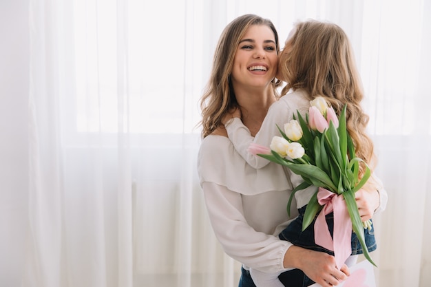 Happy mother's day. Child daughter congratulates moms and gives her flowers tulips.