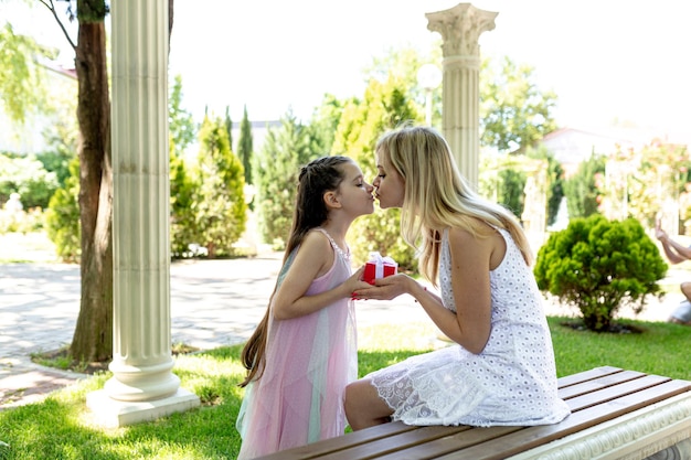 Happy mother's day Child daughter is congratulating mom and giving her gift box outdoor