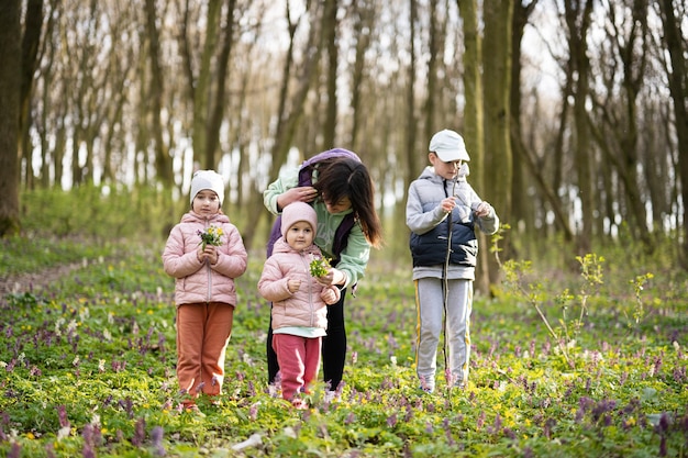 Happy Mother's Day We love you mom Mother with a bouquet of flowers and three kids in spring blooming forest