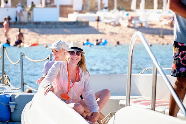 Happy mother and son on a boat on the background of the beach.