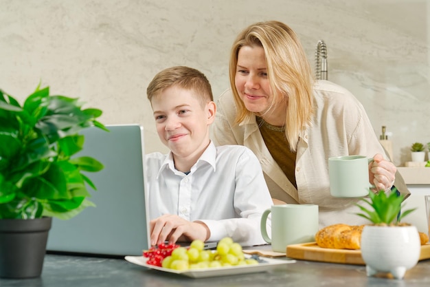 Happy mother and son have healthy breakfast in the kitchen at home breakfast and digital devices