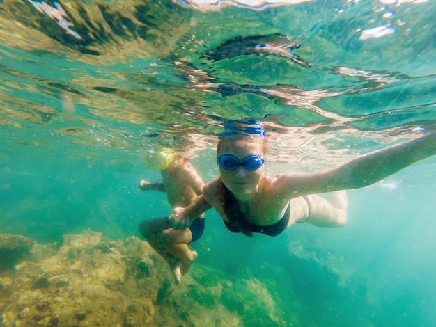 Happy mother and son snorkeling on beach.