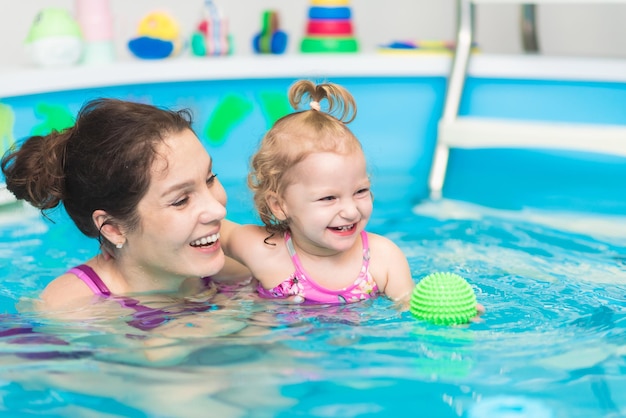 Happy mother swims in the pool with her daughter