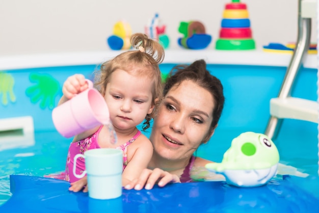 Happy mother swims in the pool with her daughter