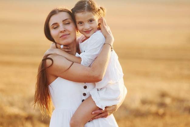 Happy mother with her little daughter spending time together outdoors on the field