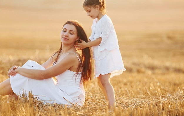 Happy mother with her little daughter spending time together outdoors on the field