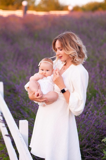 Happy mother with pretty daughter on lavender background. Beautiful woman and cute baby