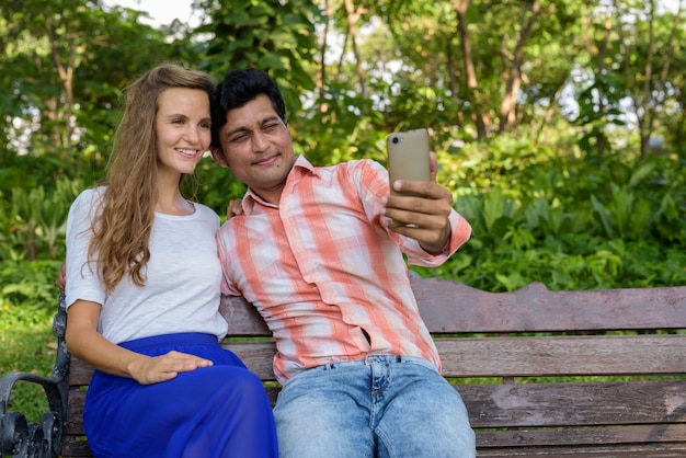 Happy multi ethnic couple smiling while taking selfie picture