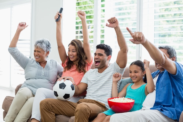 Happy multi-generation family watching soccer match on television in living room