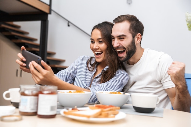 Happy multiethnic couple having breakfast at the kitchen