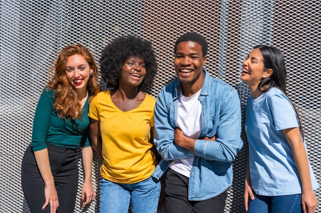 Happy multiethnic friends in the city on a gray wall young models smiling