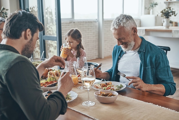 Happy multigeneration family communicating and smiling while having dinner together