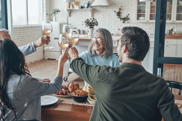 Happy multigeneration family toasting each other and smiling while having dinner together