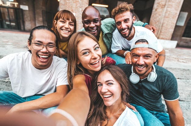 Happy multiracial friends taking selfie with smart mobile phone outdoors