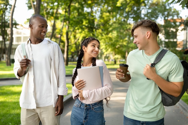 Happy multiracial university students walking together in park or in college campus chatting