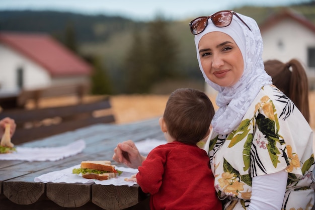 Happy Muslim family eating at a table in the park while picnicking on the summer vacation holiday