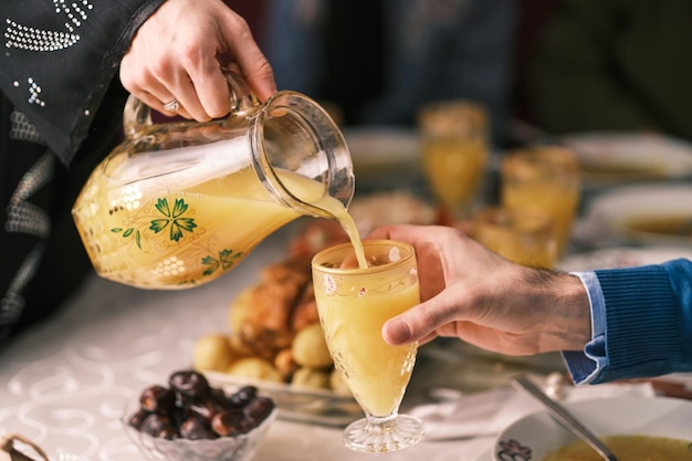 Happy Muslim family having iftar dinner during Ramadan dining table at home drinking a orange juice