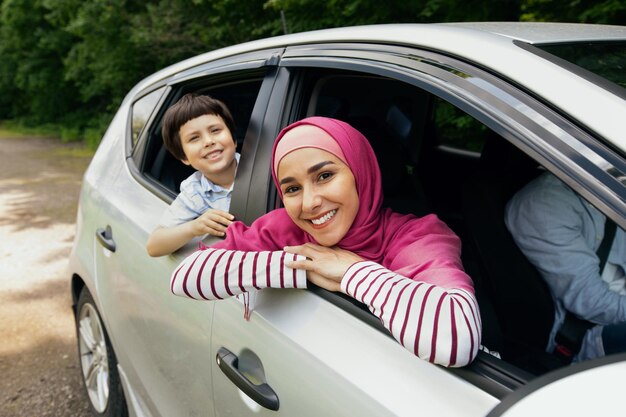 Happy Muslim Family Riding Car Together, Smiling Mother In Hijab And Son Leaning Out Of Windows, Cheerful Arab Parents And Little Male Child Enjoying Travel In Their New Vehicle, Closeup Shot