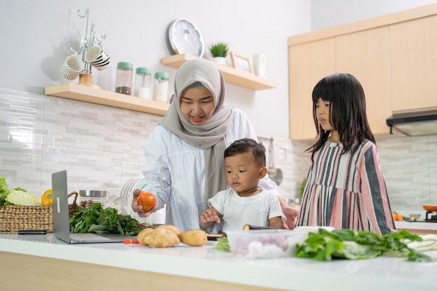 Happy muslim mother and her children cook and having fun together at home preparing for iftar dinner