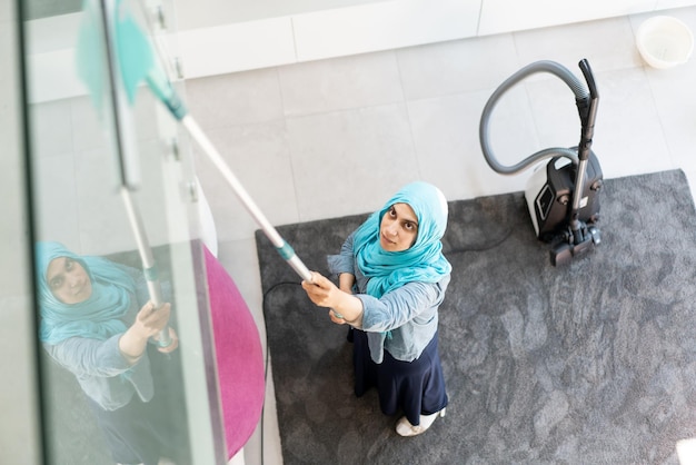 Happy Muslim Woman Cleaning Modern House Living Room. High quality photo