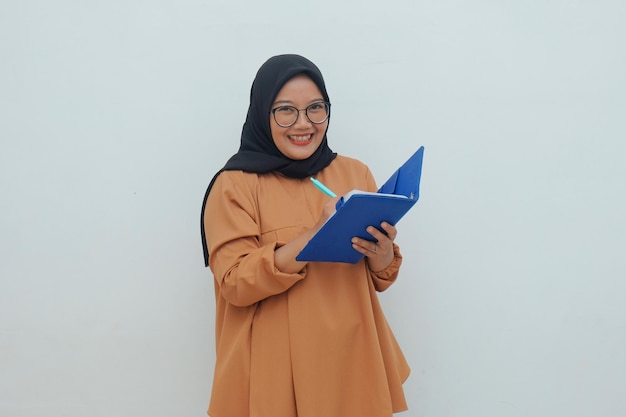 Happy muslim woman writing something in book