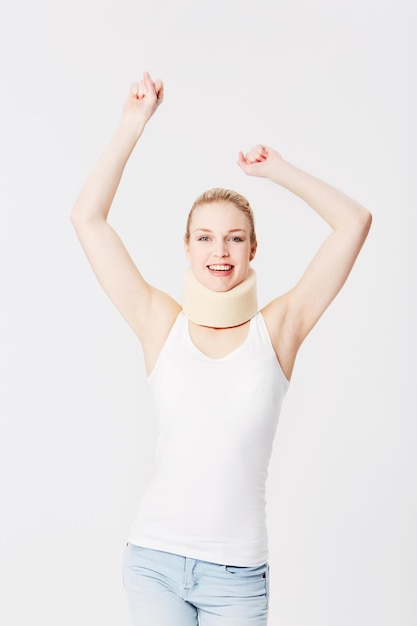 Happy neck brace and portrait of a woman with freedom isolated on a white background Smile excited and girl with arms up for accident insurance healthcare and medical attention with whiplash