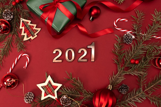 Happy New Year 2021. Golden digits 2021 with christmas hat are on red background with glitter. Holiday Party Decoration or postcard concept with top view and copy space.