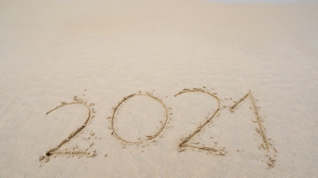 Happy New Year 2021 Text on the beach, 2021 year message hand written in sand on beautiful beach Copy space on sandy beach background. New Years concept.