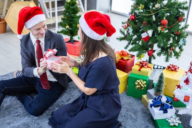 Happy new year 2022, concept,Happy couple of wrist in a business suit holding exchanging gifts and Give a present in Christmas and New Year's Eve party Christmas tree After finishing business work