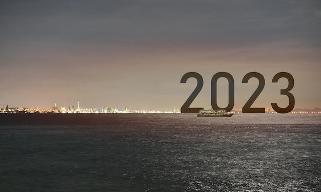 Happy new year 2023 boat on sea city night light success concept island sea cityscape at night lighting view success with sunset background Happy New Year 2023 use for web banner and advertisement